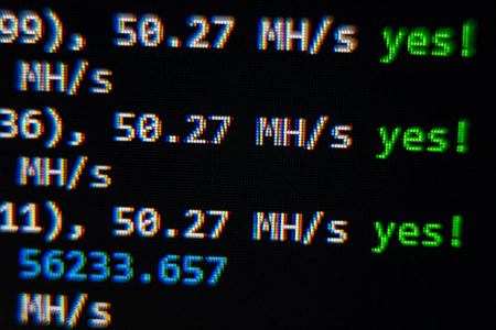 Close-up image of the computer s screen showing the blur of the programing code and a word BITCOIN...