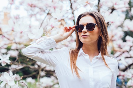 Portrait of young woman in the flowered garden in the spring time. Almond flowers blossoms