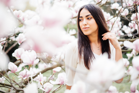 Beautiful girl in a blooming garden with magnolias. Magnolia flowering, tenderness.の写真素材