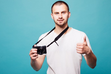 Picture of handsome emotional young man photographer isolated over green wall background holding...