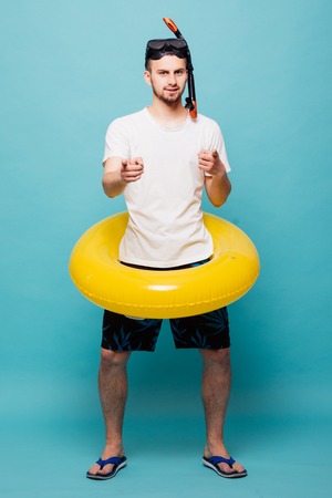 Young handsome man with inflatable yellow ring and snorkel isolated on green backgroundの写真素材