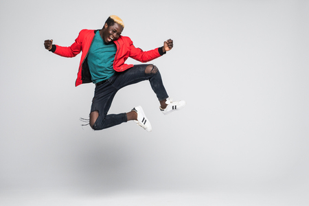 Portrait of a cheerful afro american man jumping isolated on a white backgroundの写真素材