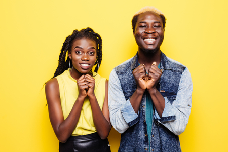 Portrait of a happy young afro american couple screaming and celebrating isolated over yellow backgroundの写真素材