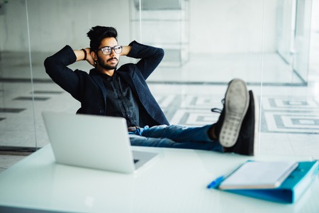 Businessman working in his office with feet on deskの写真素材