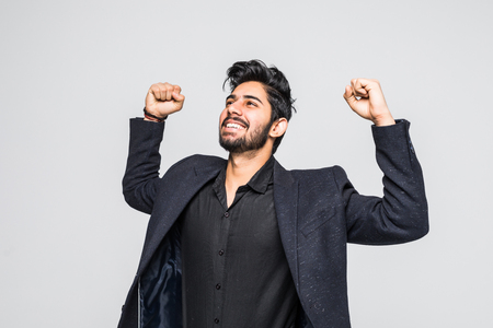 Portrait of excited Asian Indian businessman celebrating success over whiteの写真素材