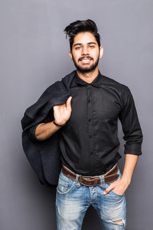 Portrait of a handsome serious businessman holding jacket on shoulders over gray background. Looking at cameraの写真素材