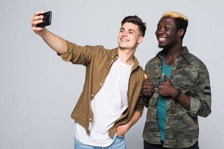 Two mixed race friends take selfie on the phone on white backgroundの写真素材