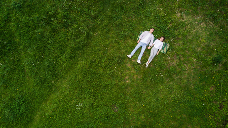 Beautiful young couple lying on the grass, view from aboveの写真素材