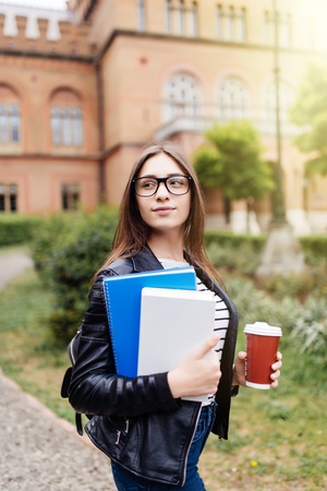 American university student smiling with coffee and book bag on campus with print spaceの写真素材