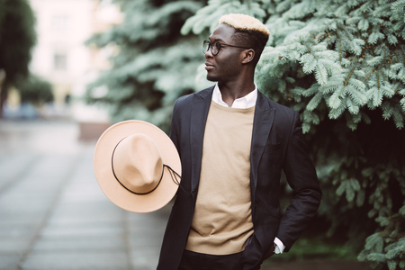 Portrait of a cool young african man in suit and hat walking in the streetの写真素材