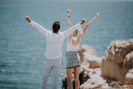 Happy couple on beach hold raised up arms, stretching hands, beautiful young happy man and woman smile, concept freedom summer ocean holiday travelの写真素材