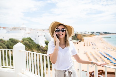 Beautiful woman leaning on the terrace railing, relaxing and having phone call