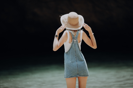 Back view of a woman wearing hat enjoying the view at the oceanの写真素材