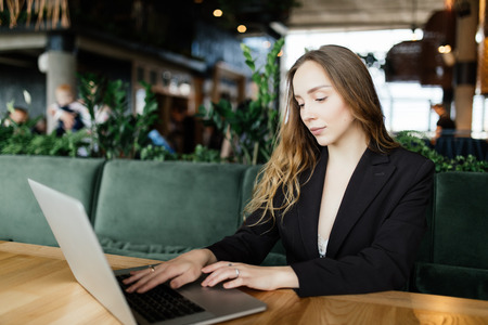 Beautiful attractive woman at the cafe with a laptop having a coffee breakの写真素材