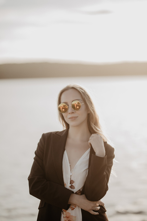 Young pretty tanned woman with sunglasses on sunset beach. Concept of summer vacationの写真素材