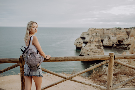 Young beautiful woman hipster traveler looking at sunset and beautiful seascape with a lookout point. Freedom, travel, vacationの写真素材