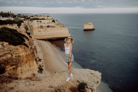Young happy Girl on the edge of stone with panorama view on the sea beach.の写真素材
