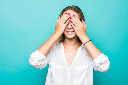 Portrait of smiling young woman covering eyes with her arms isolated over blue backgroundの写真素材