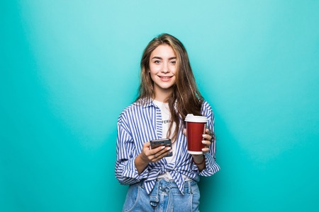 emotional happy beautiful woman lovely portrait beautiful woman talking phone and holding a take away coffee on blue backgroundの写真素材