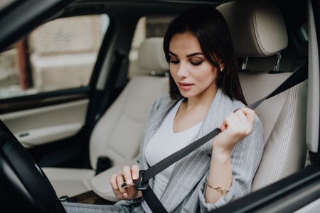 elegant woman putting on safety belt in her carの写真素材