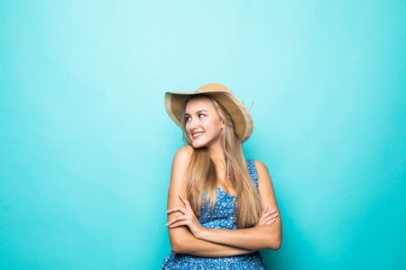 Portrait of a smiling young woman standing with arms folded and looking away at copyspace isolated...
