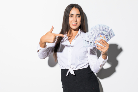 Portrait of an satisfied girl holding money banknotes and pointing finger isolated over white backgroundの写真素材
