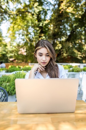 A young attractive woman sitting in a cafe with a laptopの写真素材