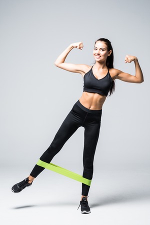 Woman exercising doing workout for legs with elastic bands on white background