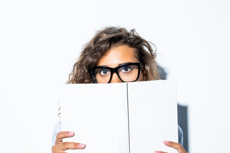 Young businesswoman looking over book cover isolated on white background