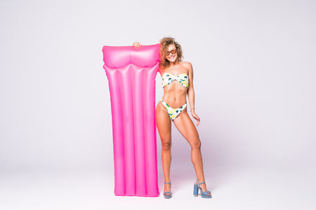 Young beautiful smiling woman in sunglasses and bikini with inflatable mattress on white backgroundの写真素材