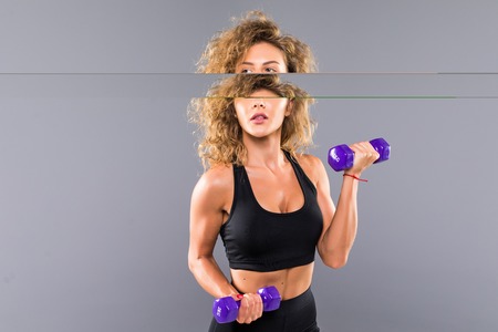 Athletic woman doing exercise for arms. Photo of muscular fitness model working out with dumbbells...