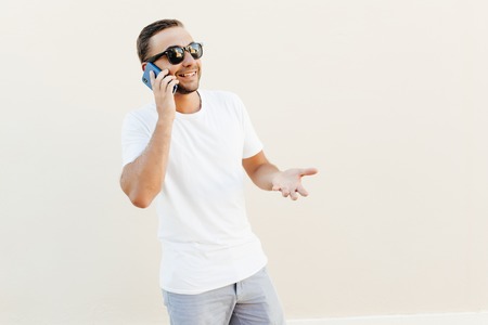 Young man in sunglasses talking on the phone on orange background.の写真素材