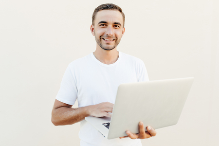 Portrait of smiling male student using a laptop on white backgroundの写真素材