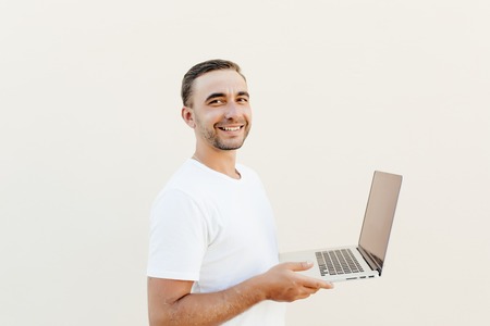 Portrait of smiling male student using a laptop on white background