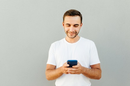 Portrait of excited using smartphone for getting sending sms isolated on gray background copy-sapce