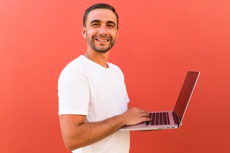 Handsome programmer with laptop on red backgroundの写真素材