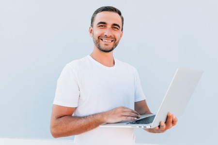 Happy Young Man Working On Laptop On Blue Backgroundの写真素材