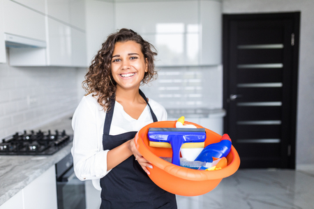 Young woman in rubber gloves holding mop and bucket with detergens. Maid cleaning at homeの写真素材