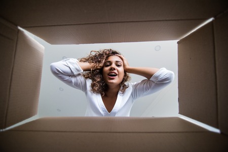 Mixed race Woman unpacking carton box when moving home .の写真素材