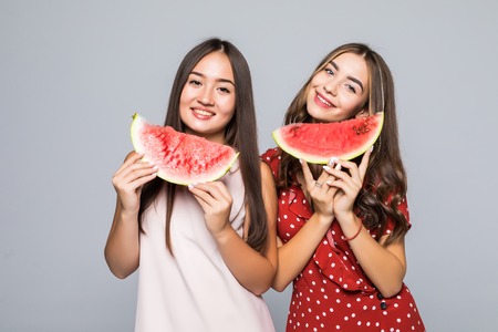 Two beautiful young mixed race woman smiling while holding a watermelon in his hands.の写真素材