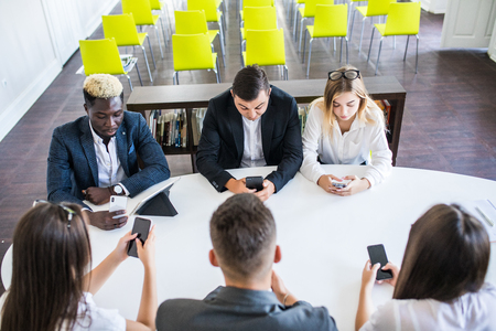 business, people and technology concept - creative team with laptop and tablet pc computers displaying charts on screens sitting at table in officeの写真素材
