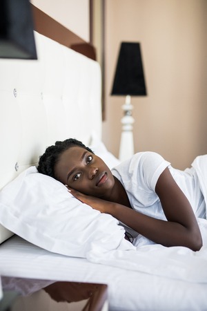 Side view of beautiful young Afro American woman smiling while sleeping in her bed at homeの写真素材