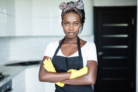 young african woman with arms crossed in the kitchenの写真素材