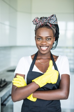 Young african woman in yellow gloves who showing thumb up in the roomの写真素材