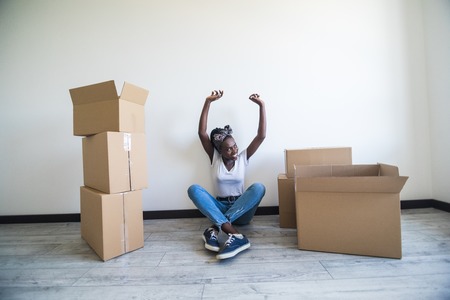 people, moving new place and repair concept - happy african american young woman with many cardboard...