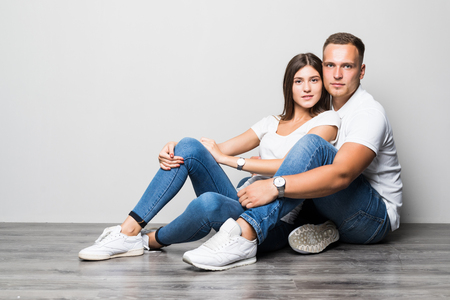 Portrait of a happy young couple sitting together over beige background, huggingの写真素材