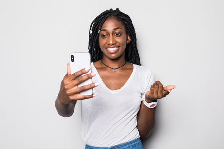 Laughing african girl smiling during video call. Indoor photo of optimistic black lady making selfie on white background.の写真素材