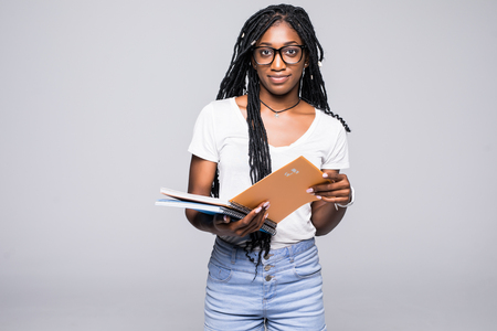 Portrait of a smiling afro american woman holding notebook with pencil over gray backgroundの写真素材