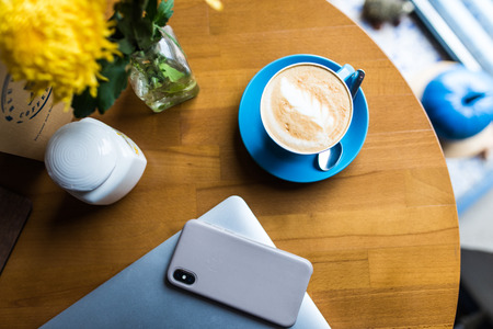 Coffee shop desk table with smartphone, laptop computer and cup of coffee.