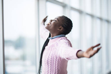 Portrait african woman with reised hands up celebrate success and goods results on pamoramic window...